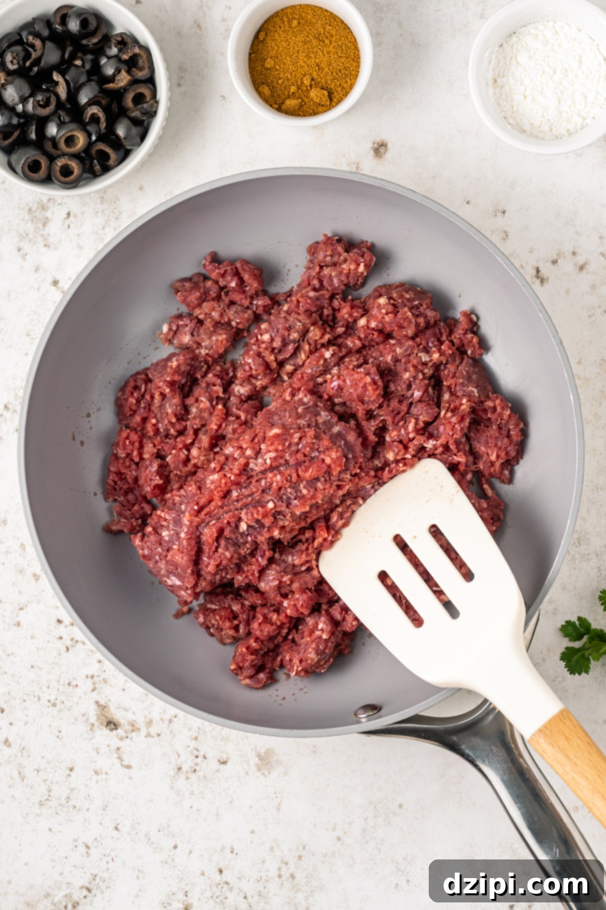 Ground beef actively browning in a skillet over medium heat, demonstrating the initial cooking stage for the taco dip.