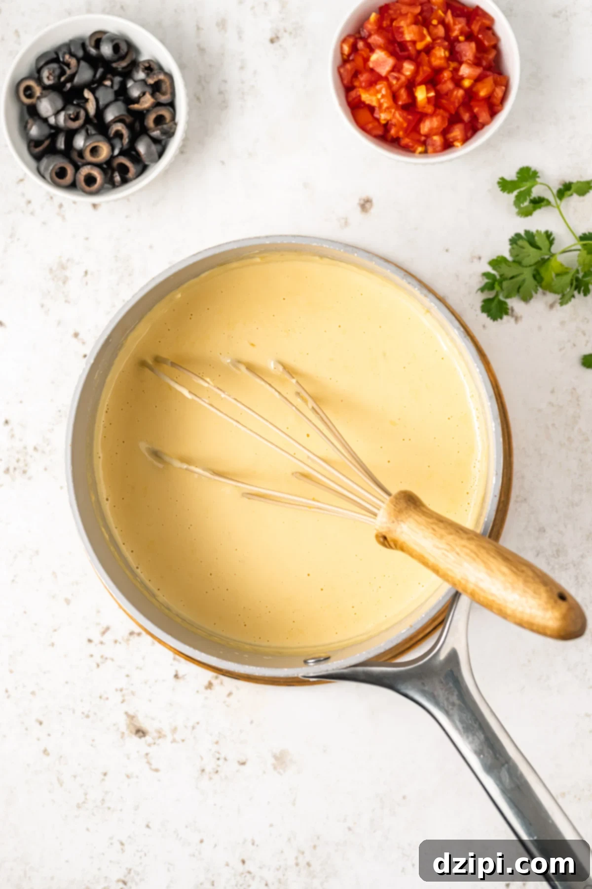 A small saucepan with a perfectly melted and thickened cheese sauce, indicating the successful completion of the queso base.