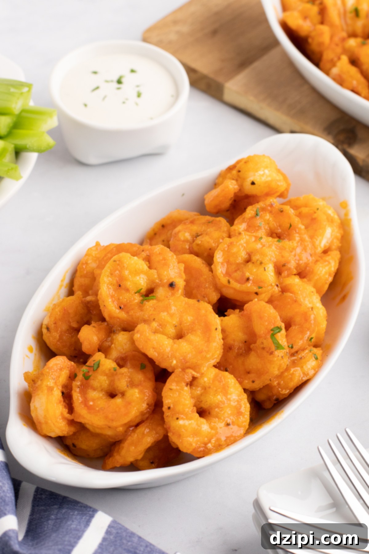 A close-up of several buffalo shrimp on a white plate, garnished with fresh parsley.