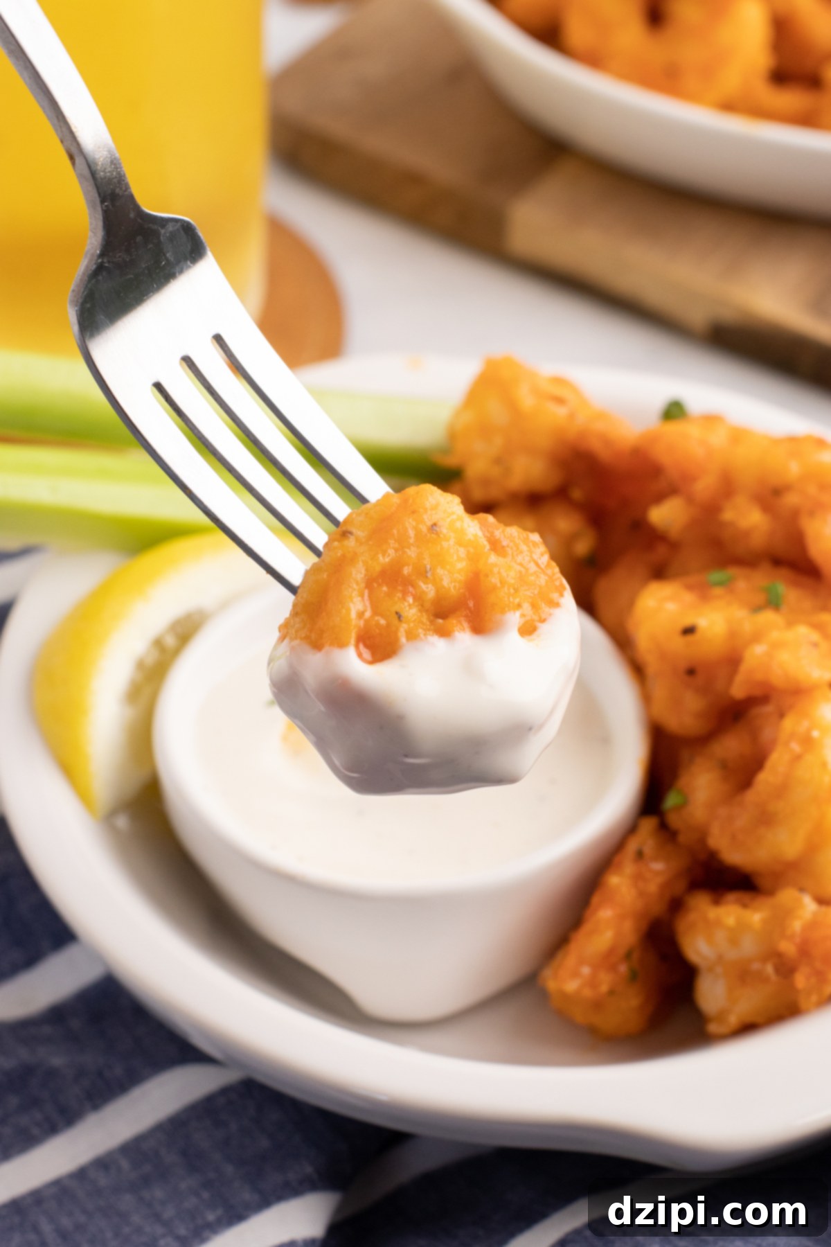 A fork holds up a buffalo shrimp that has been dipped in ranch dressing.