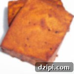 Two blocks of smoked tofu that have been turned a deep red by the barbecue sauce sit on a white serving plate.