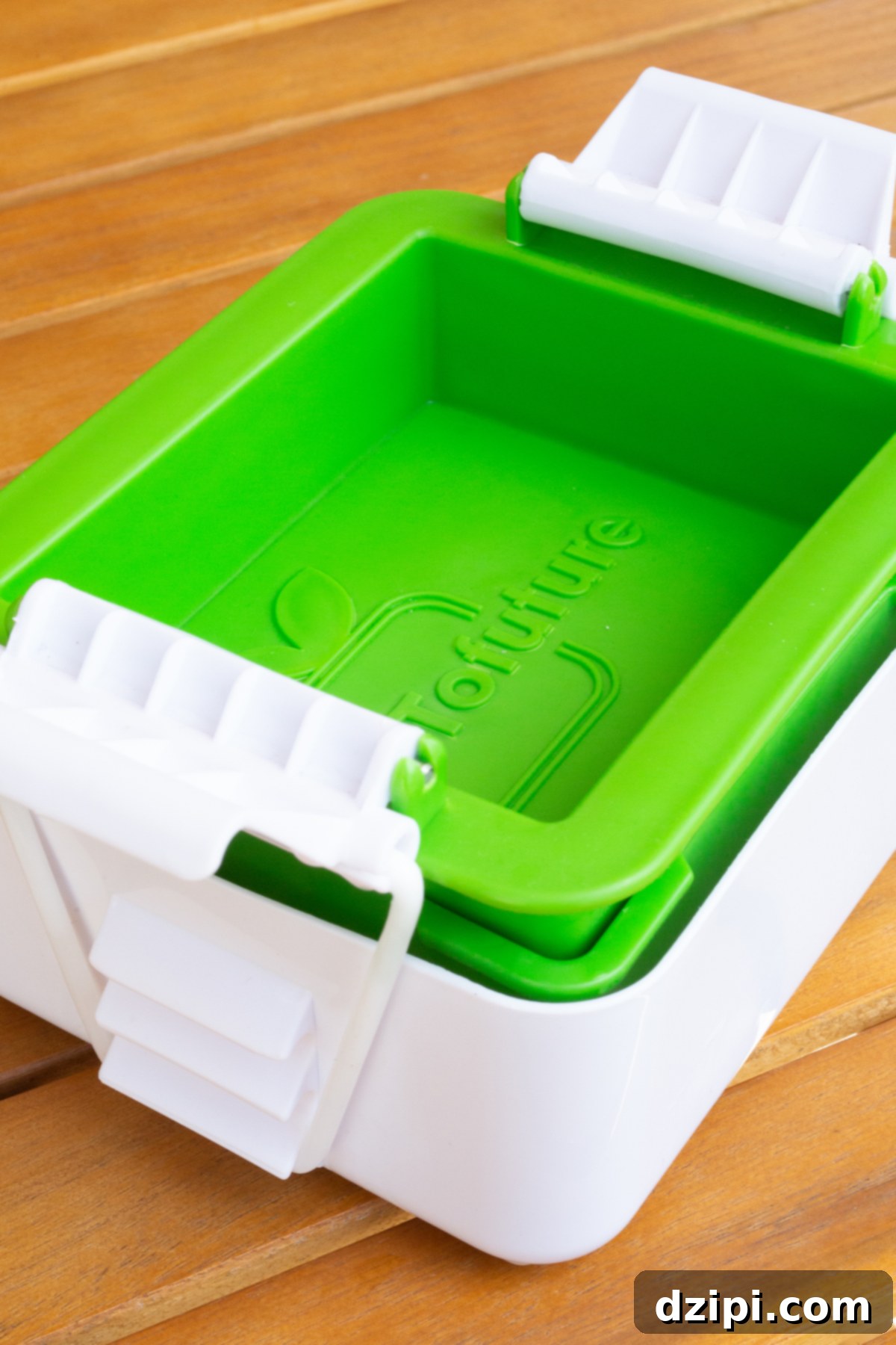 Block of tofu being pressed using a tofu press.