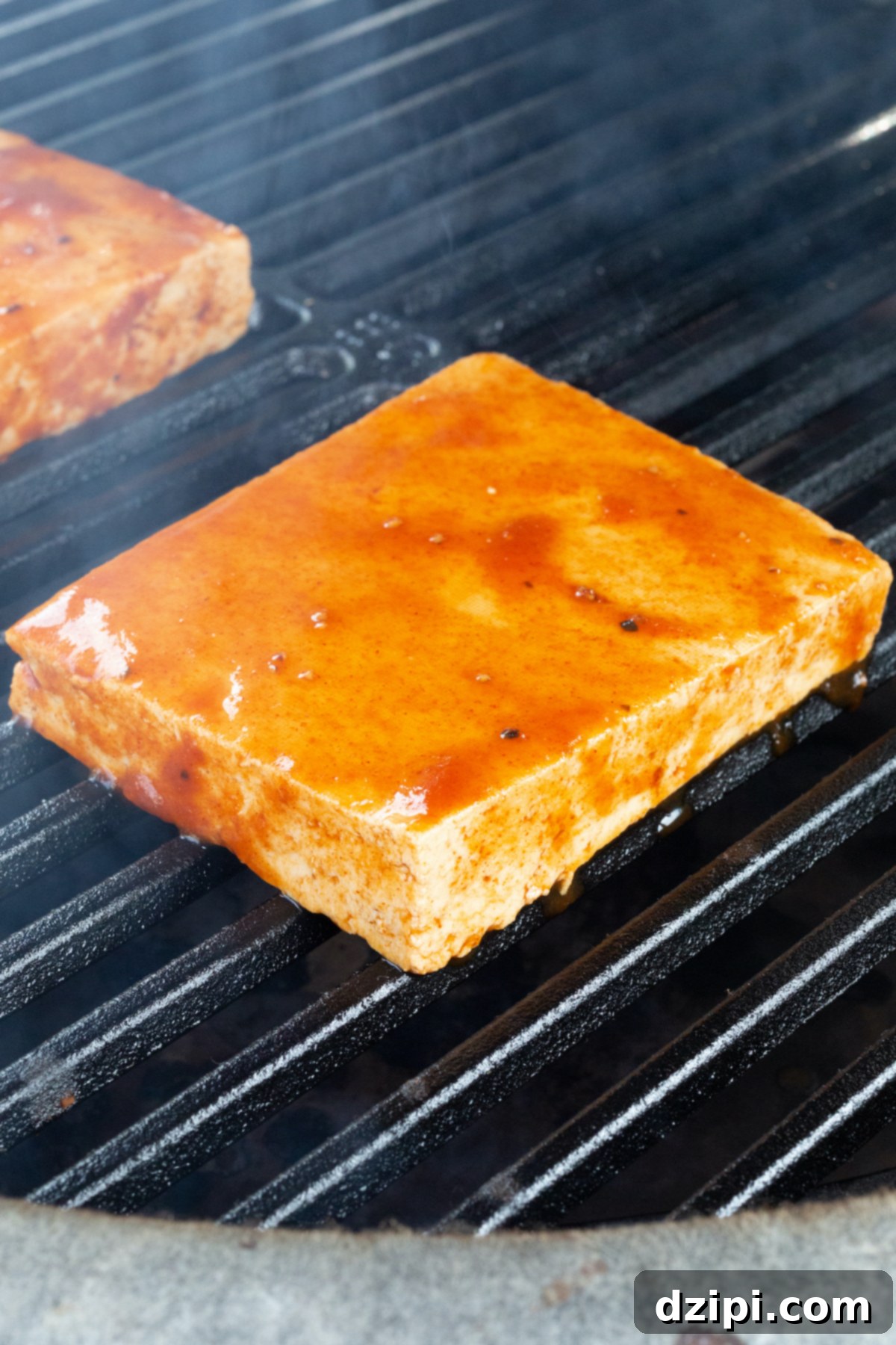 Tofu blocks smoking on a grill grate.