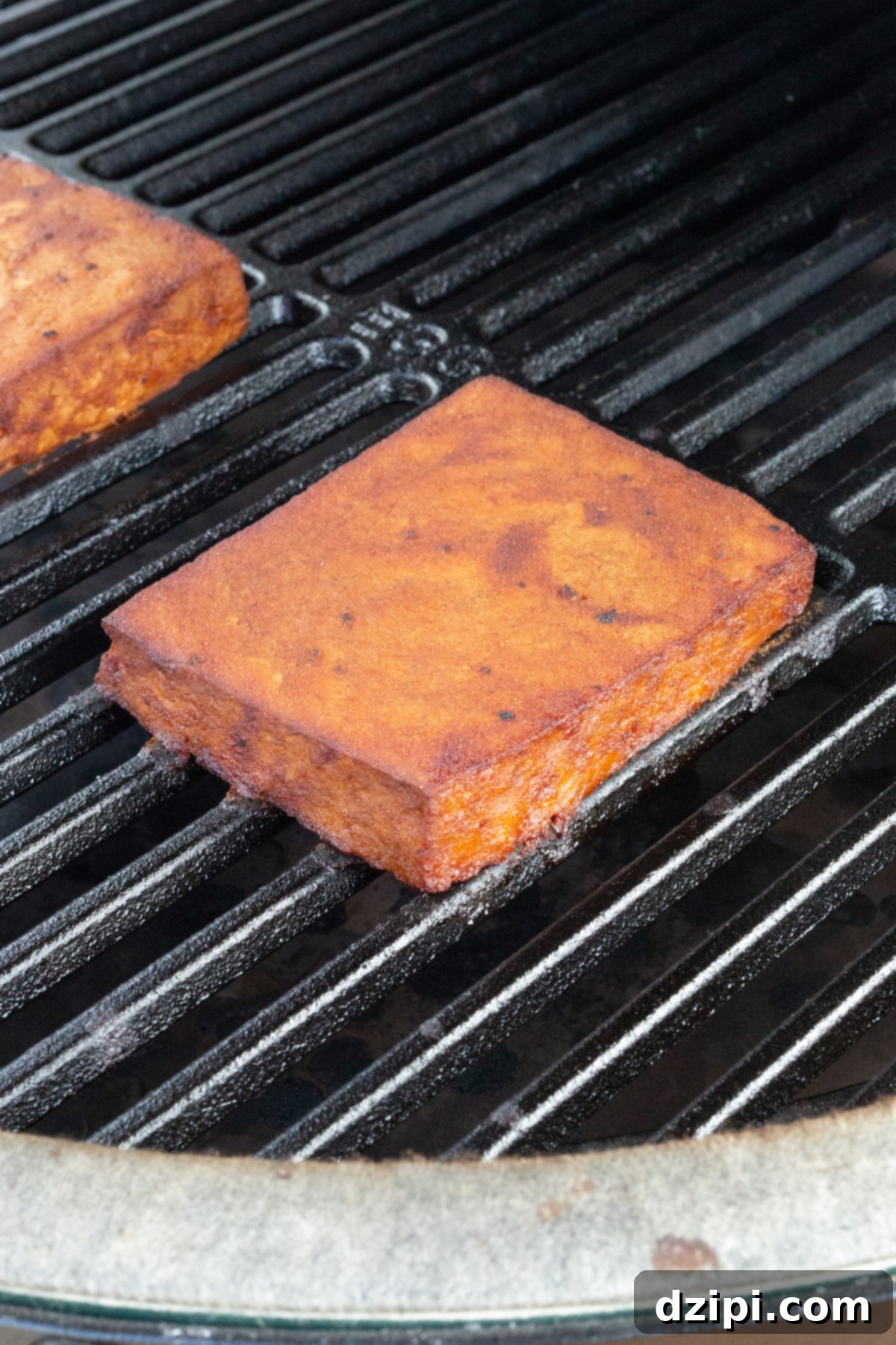 Close-up of smoked tofu on a serving plate, showing its reddish-brown color and slightly crisp edges.