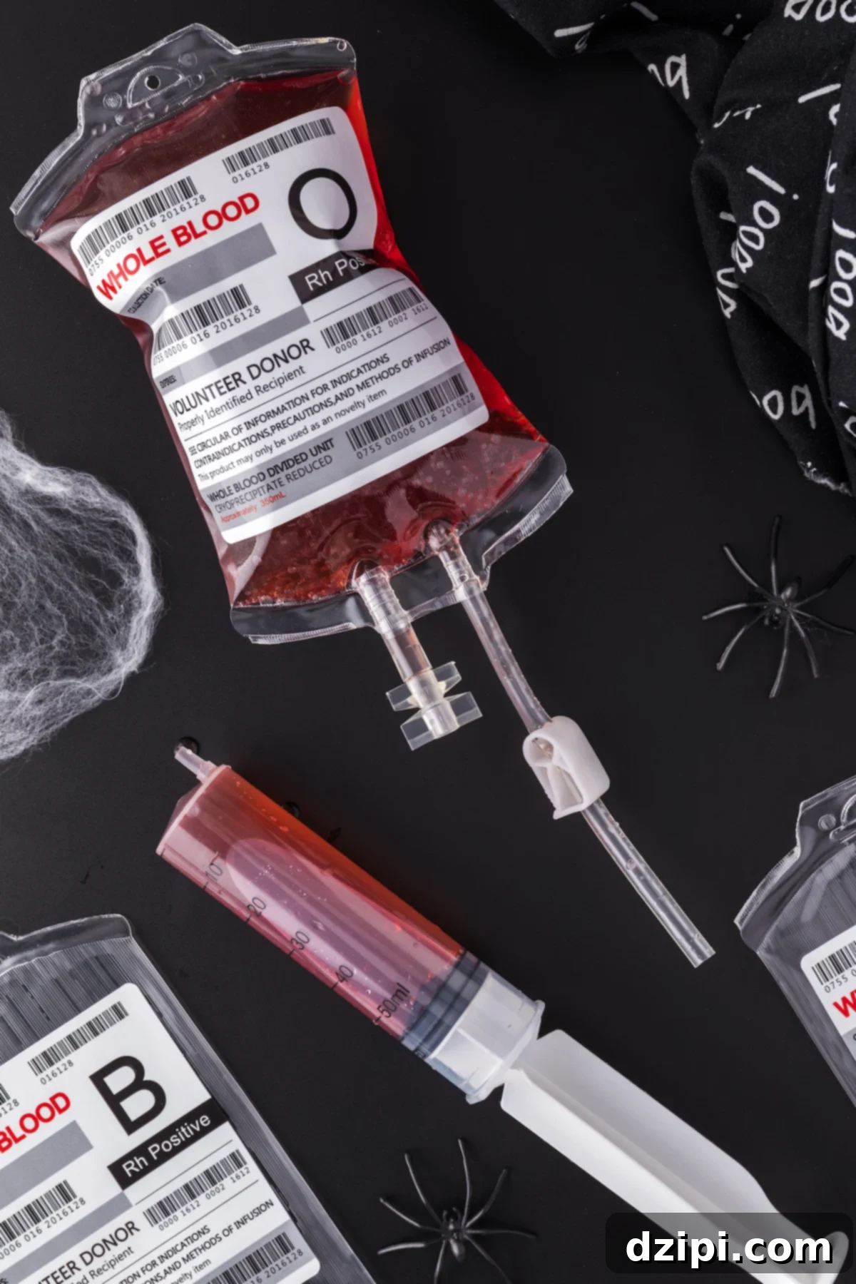 A fake "IV bag" has been filled with Halloween punch that looks like blood. A plastic syringe sits next to it.