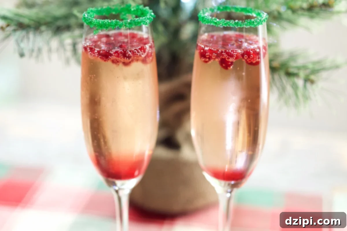 Two festive Christmas Champagne Cocktails in elegant champagne flutes, set against a backdrop of a twinkling mini Christmas tree, evoking holiday cheer.