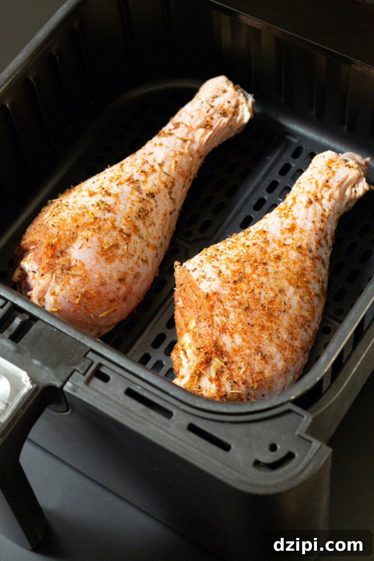 Raw, seasoned turkey legs carefully arranged in an air fryer basket, ready for cooking.