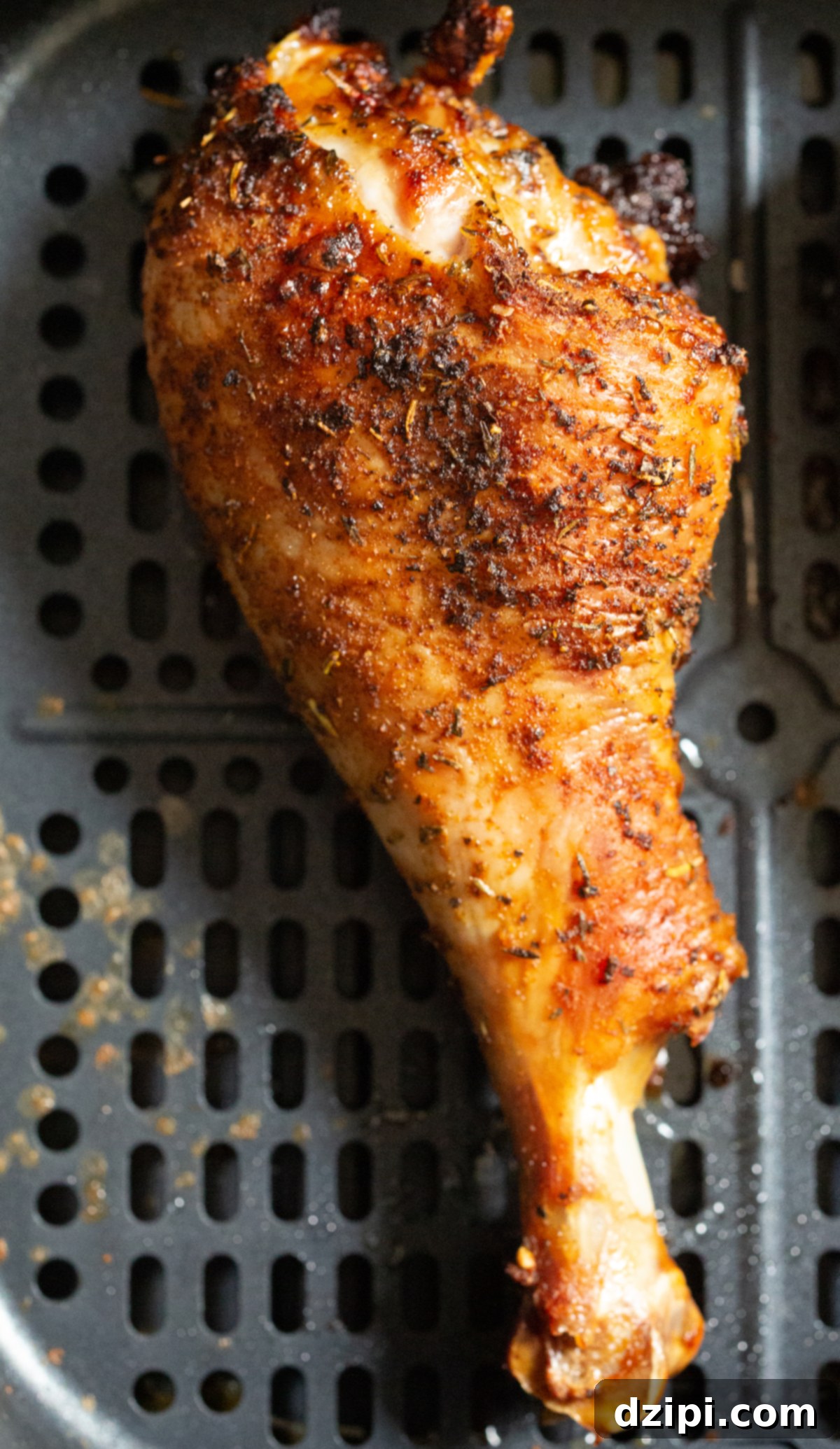 A single perfectly cooked, golden-brown turkey leg resting elegantly in an air fryer basket, highlighting its crispy skin and appealing presentation.