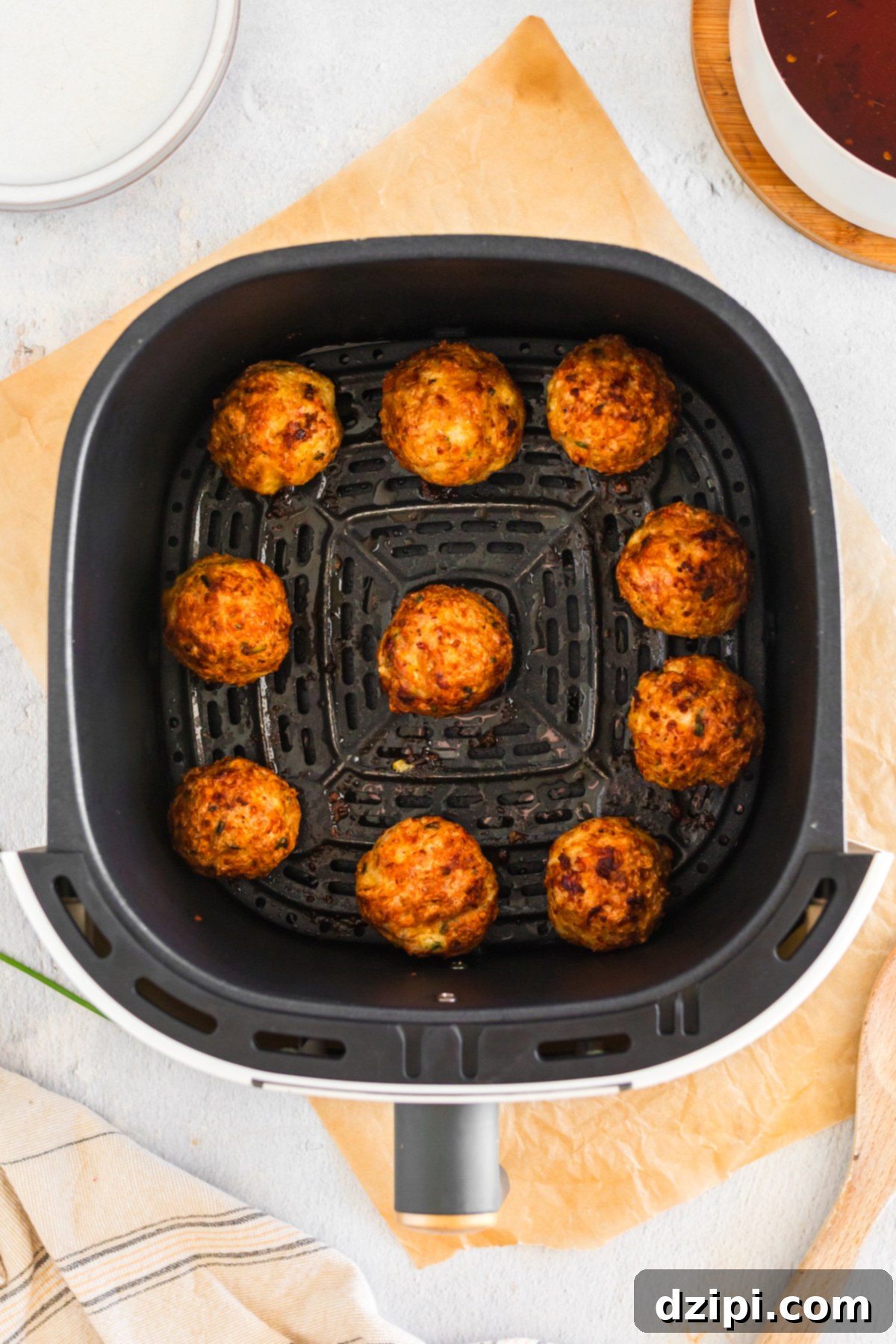 An air fryer basket with 10 cooked firecracker meatballs.
