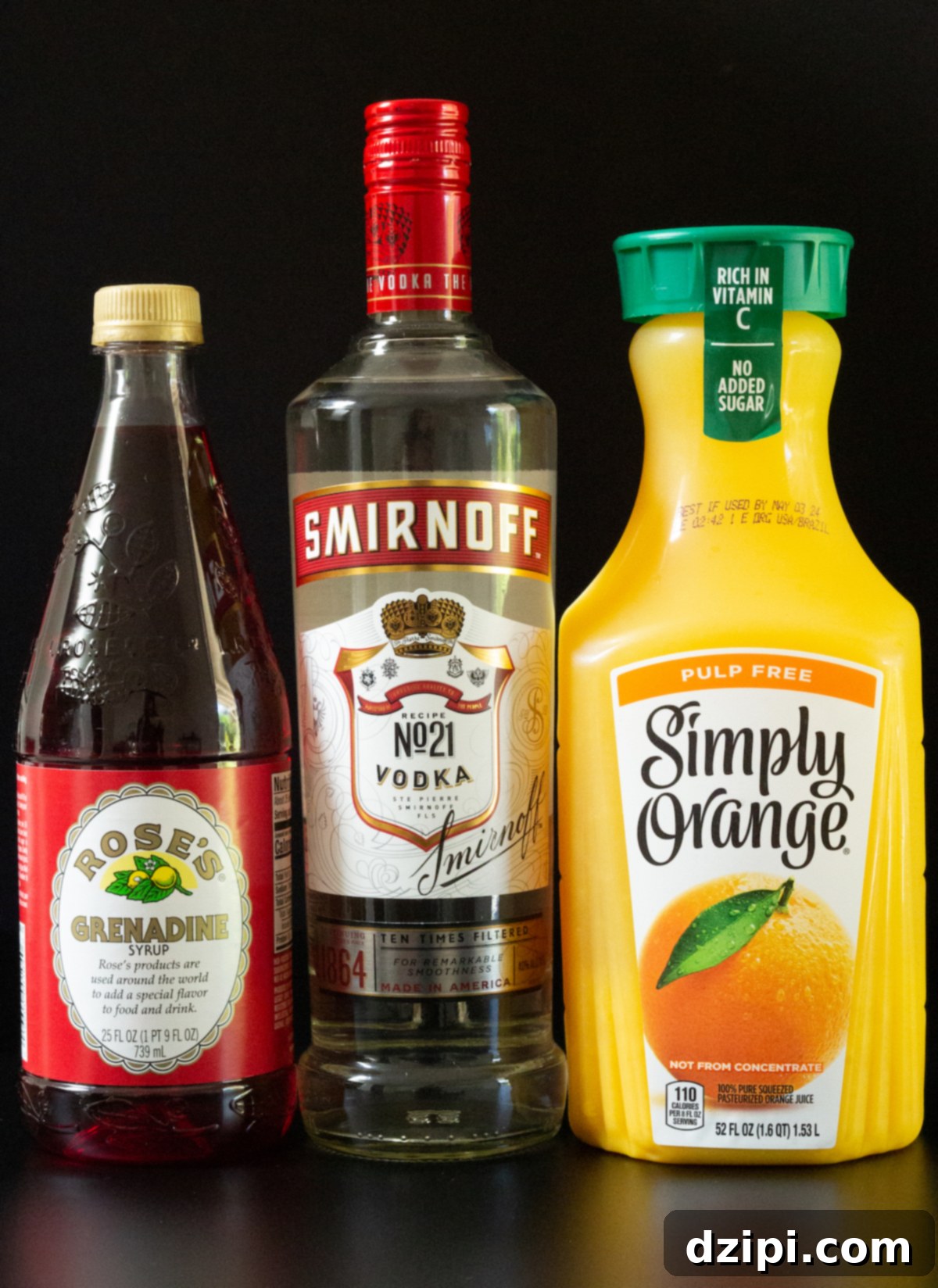 A stylish flat lay of essential Vodka Sunrise ingredients: a bottle of premium vodka, a pitcher of freshly squeezed orange juice, and a bottle of bright red grenadine, all arranged on a dark, elegant background.
