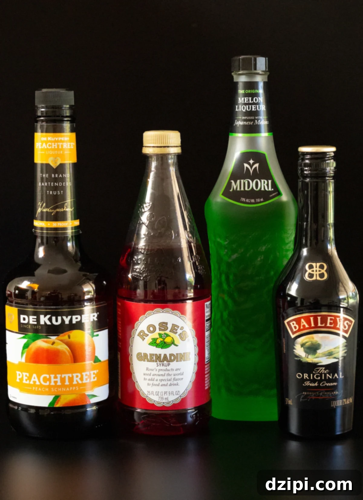 A bottle of peach schnapps, Rose's grenadine, Midori, and Bailey's Irish Cream on a black background.