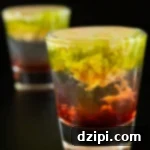 Two shot glasses with the bottom filled with a red liquid, middle is clear, and top is brown and green with the texture of brains.