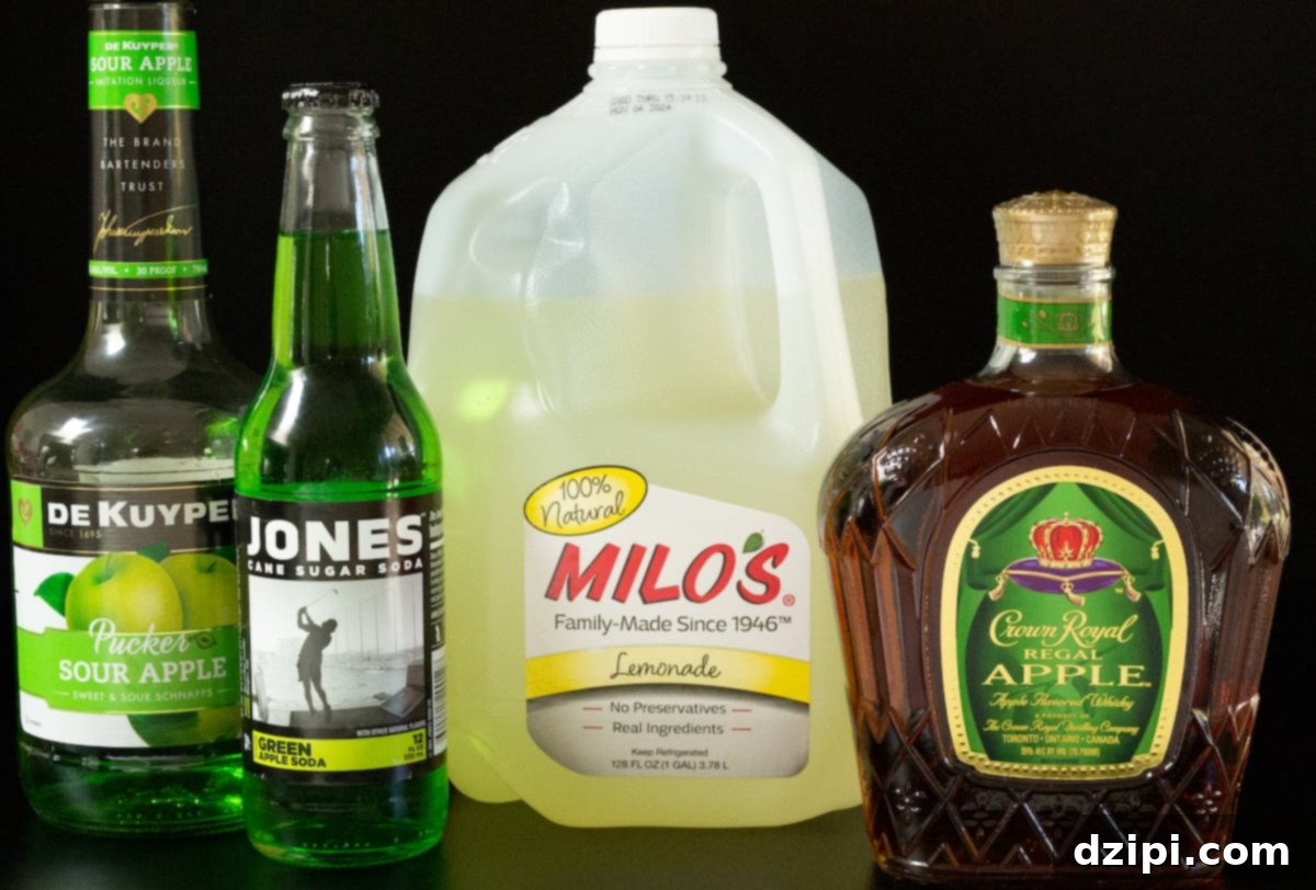 Crown's Crisp Green Apple Slush 3 A collection of ingredients for the Crown Apple Slushie, including a bottle of Sour Apple Pucker, a bottle of Jones Green Apple Soda, a bottle of Crown Royal Apple whiskey, and a gallon of lemonade, laid out for easy viewing.