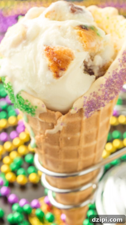 A waffle cone filled with king cake ice cream. Mardi gras beads are in the background out of focus.