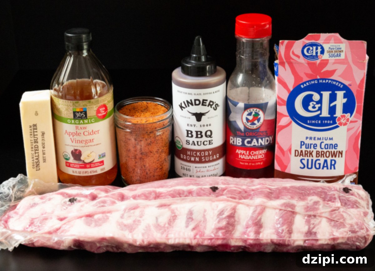 A selection of ingredients for candied ribs: a stick of butter, a bottle of apple cider vinegar, a container of BBQ seasoning, BBQ sauce, a bottle labeled "rib candy," brown sugar, and a raw rack of ribs, all arranged on a dark background.