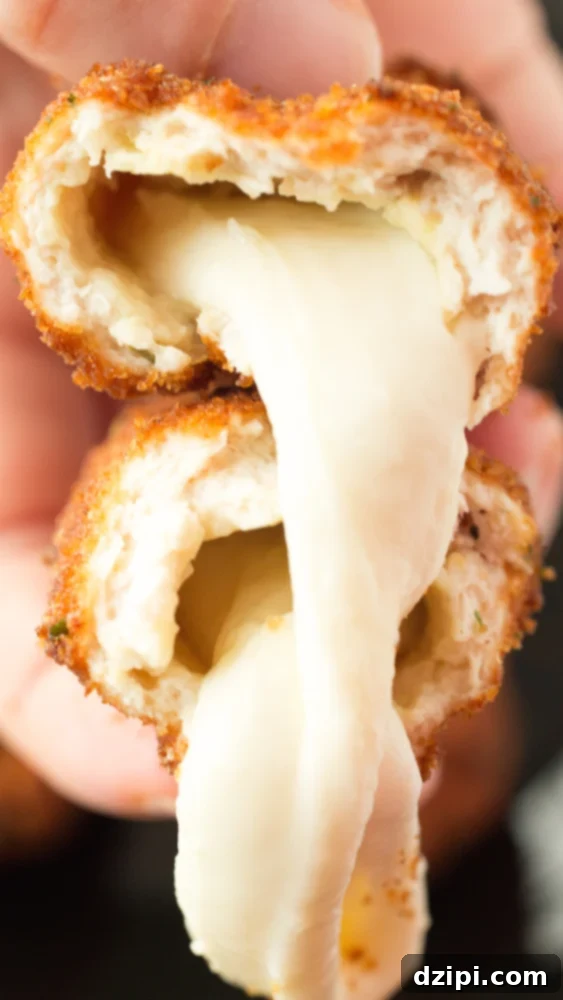 A perfectly fried Mozzarella Stick Chicken Fry sliced in half, revealing rich, melted mozzarella cheese stretching out