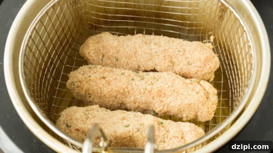 Mozzarella chicken cheese sticks arranged on a deep fryer basket, ready for cooking