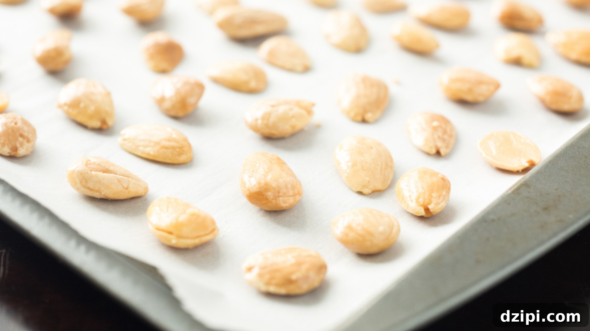 Perfectly arranged Marcona almonds on parchment paper on a baking mat, ready for their transformation.