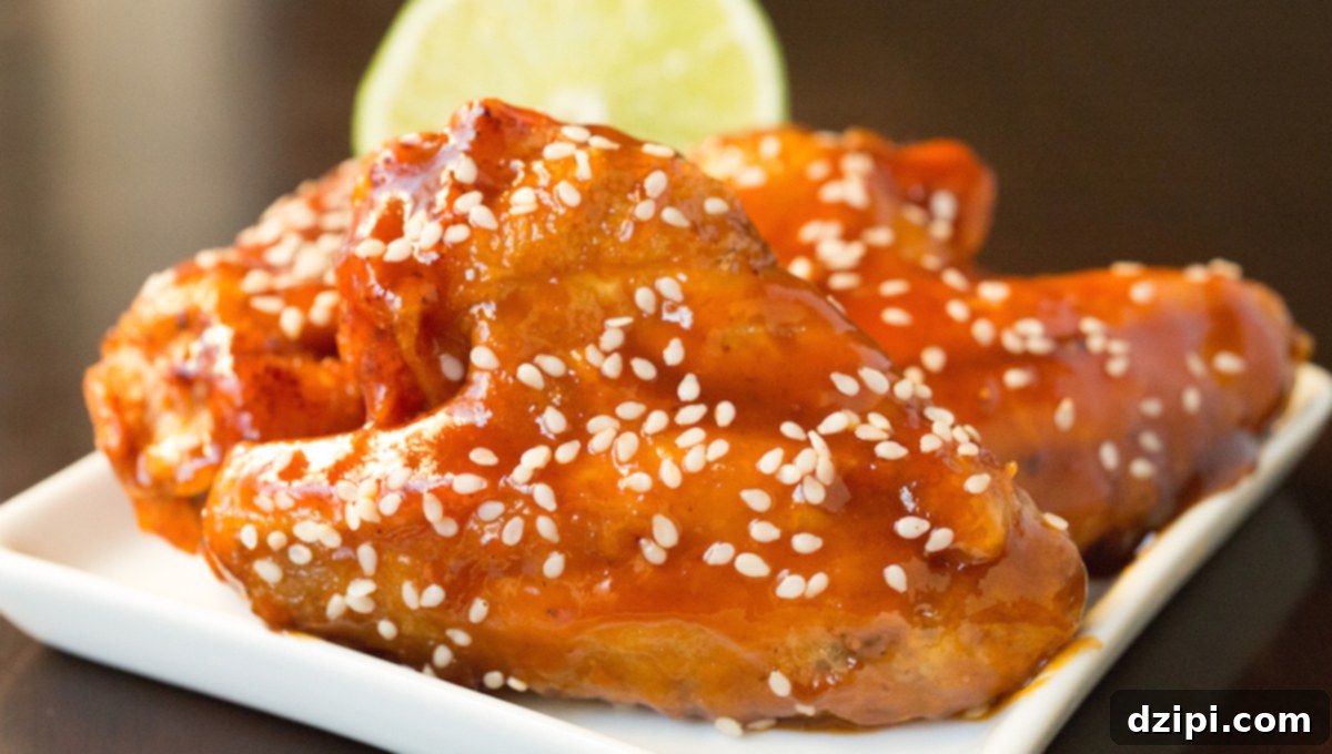 Sticky Honey Sriracha Wings 7 Horizontal view of honey lime sriracha chicken wings sitting on a small white appetizer plate.