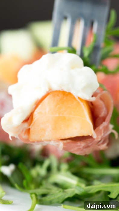 Creamy Burrata, Sweet Melon, and Savory Prosciutto Salad 4 A fork lifts a perfectly portioned bite of cantaloupe, elegantly wrapped in a thin slice of prosciutto, and adorned with a creamy dollop of fresh burrata cheese. The ingredients are perfectly balanced for a delightful mouthful.