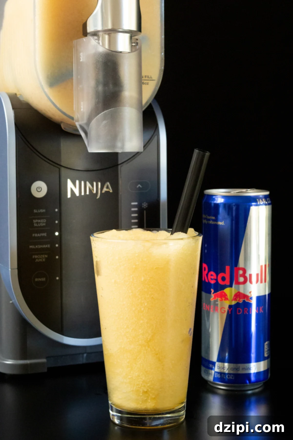 Red Bull Freeze 2 A pint glass filled with a light brown Red Bull slushie is in focus in the foreground, a Ninja Slushi machine and a can of the energy drink are out of focus in the background.
