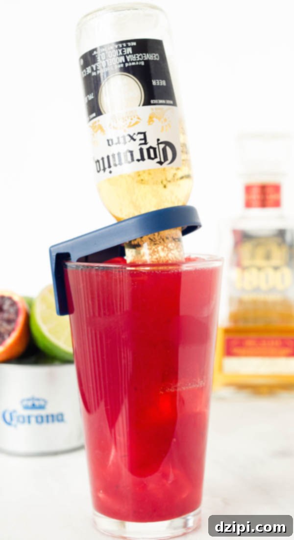 The Perfect Blood Orange Lemongrass CoronaRita 6 Four tall glasses filled with Blood Orange CoronaRitas, each with an inverted Coronita beer, garnished with fresh blood orange slices. The drinks are placed on a rustic wooden board, ready for a festive gathering.