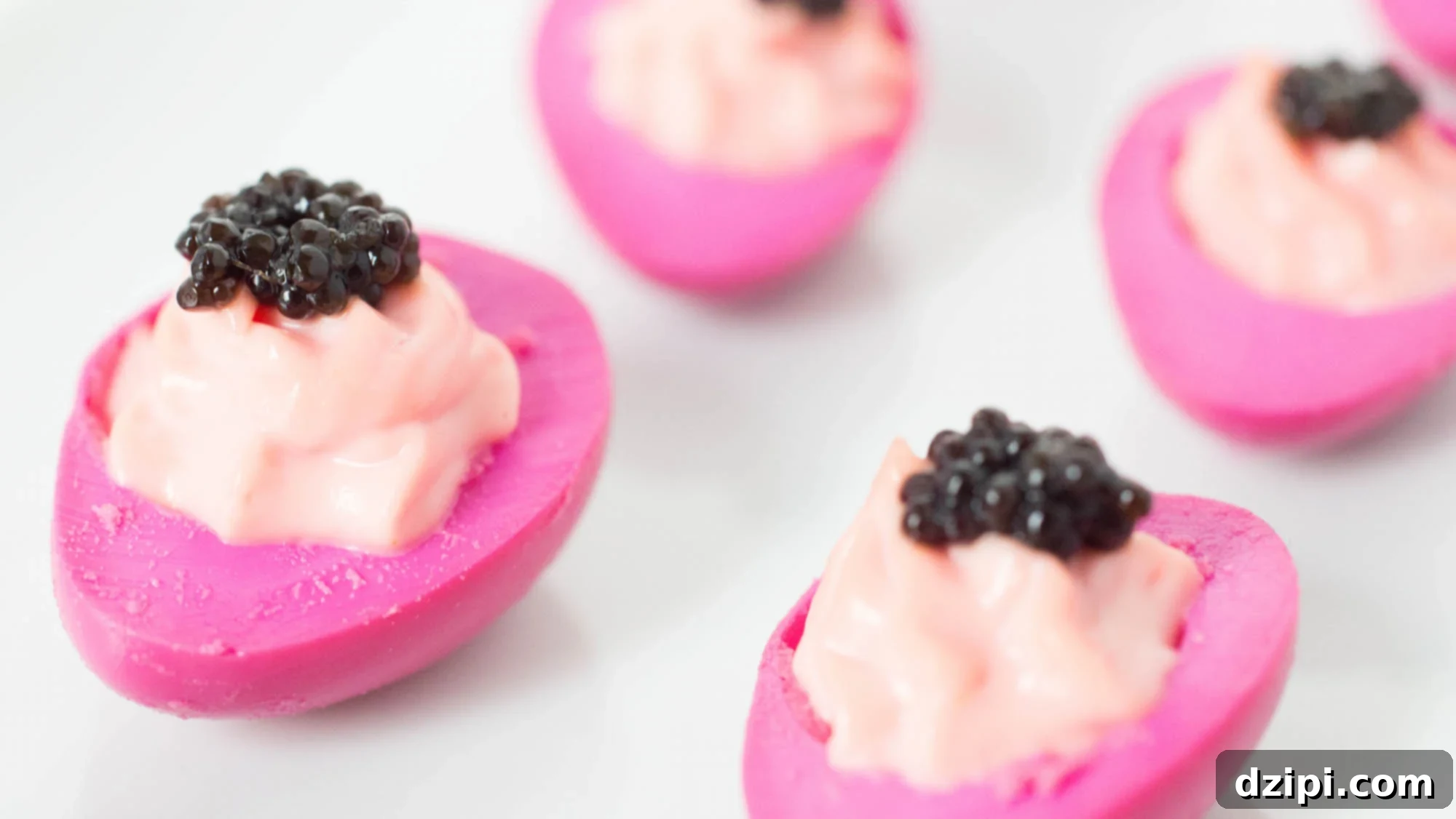 A close-up of four perfectly pink deviled quail eggs, each elegantly topped with a delicate dollop of black caviar, presented on a minimalist platter.