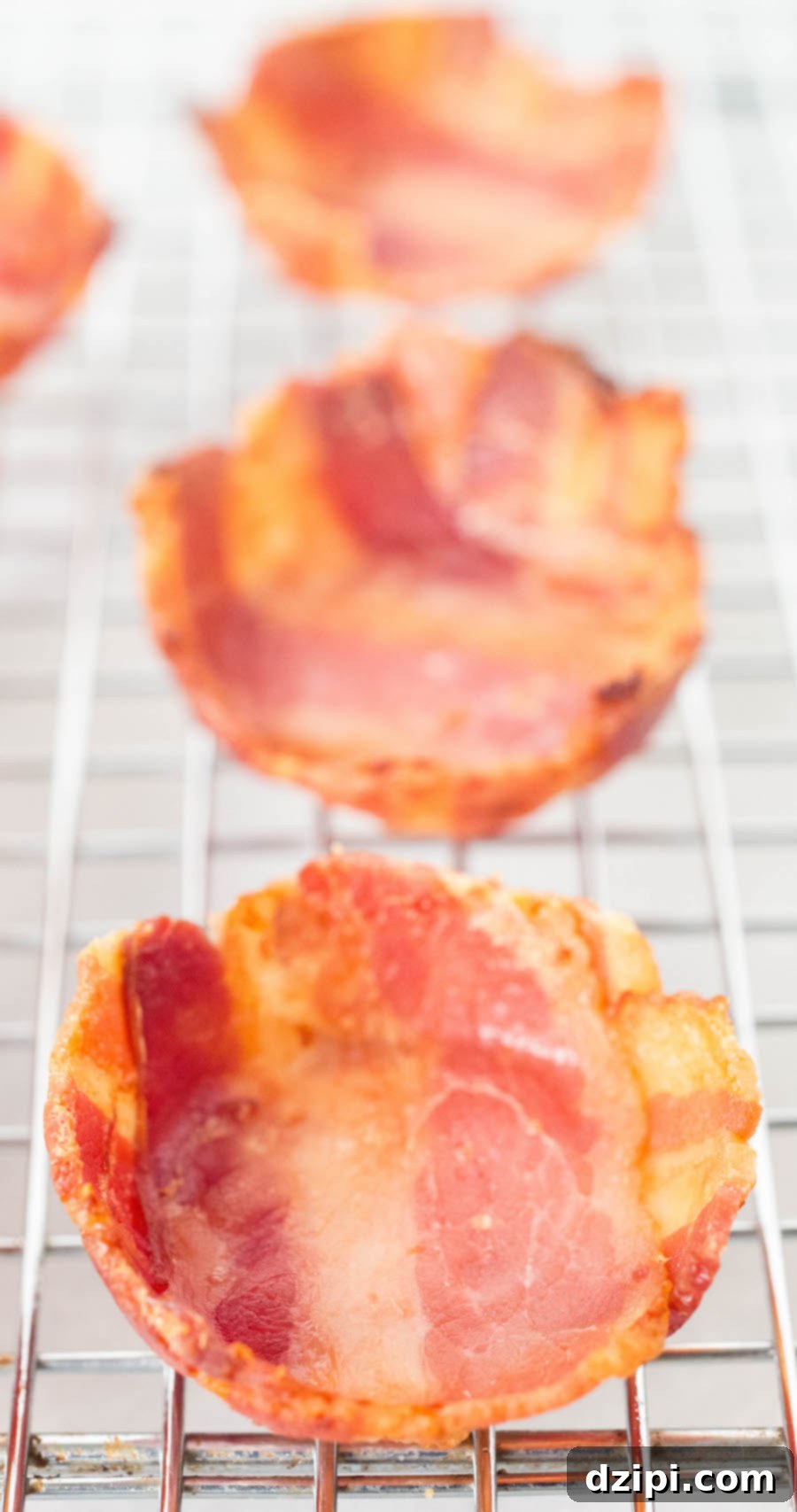 A wire rack holds perfectly formed, golden-brown mini bacon cups, ready to be filled with delicious baked beans.