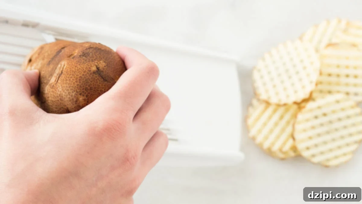 Loaded BLT Waffle Fries 4 Overhead view of a hand slicing a potato on a waffle mandolin.
