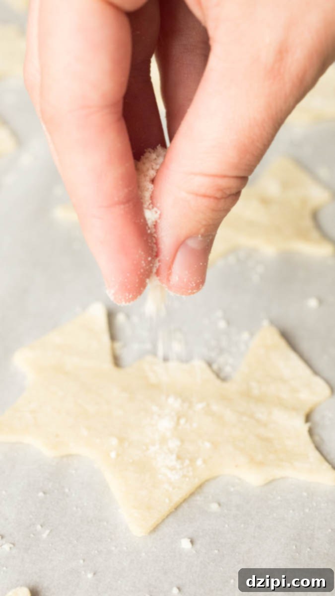 Spooktacular Tortilla Chip Trio 5 A baking sheet is filled with delicate bat-shaped tortilla chips, being generously seasoned with a savory garlic parmesan blend, showcasing the flavorful preparation stage before they are baked to perfection.