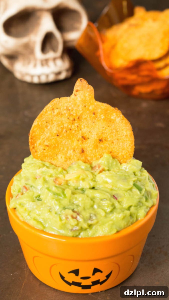 Spooktacular Tortilla Chip Trio 8 Beautifully textured homemade pumpkin-shaped Halloween tortilla chips, expertly seasoned with a blend of spices, are shown being deliciously dipped into a luscious bowl of creamy green guacamole, highlighting their festive appeal and perfect pairing.