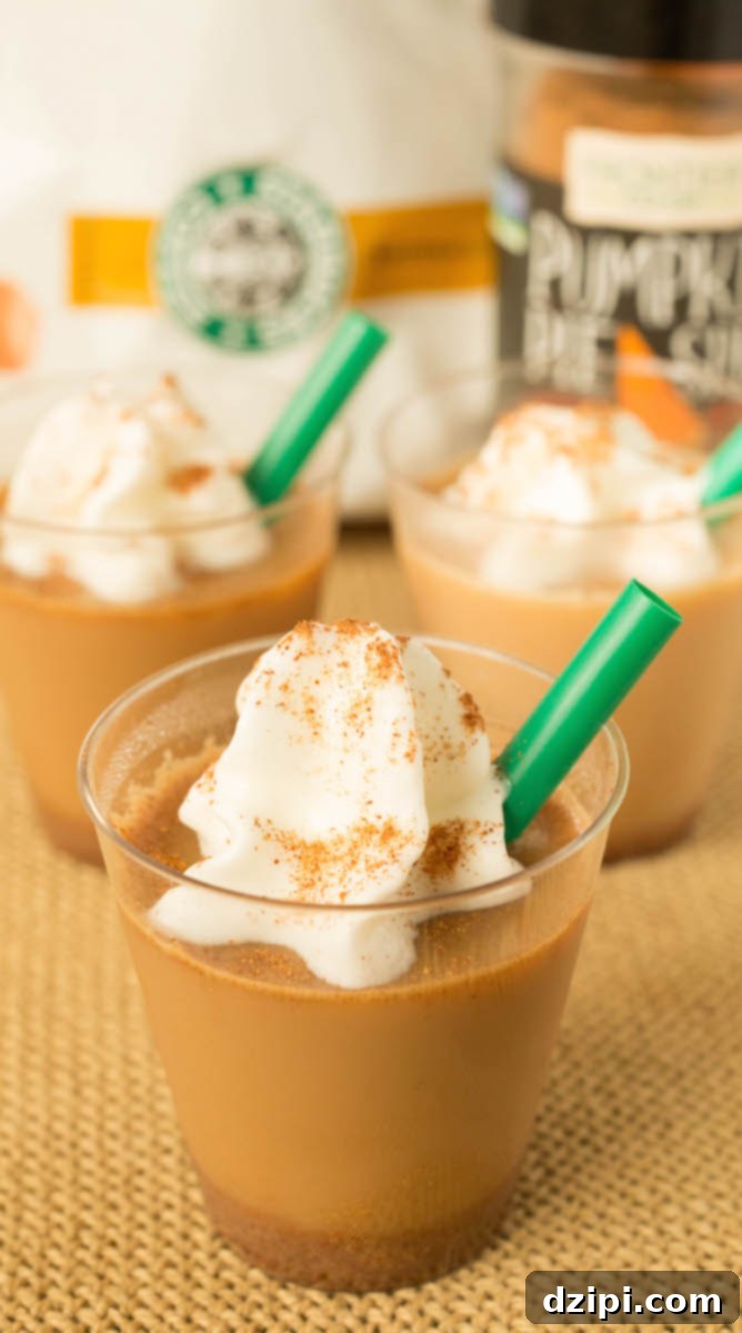 Pumpkin Spice Latte Jello Shot Bliss 4 Close-up of a single Pumpkin Spice Latte Jello Shot in a mini plastic cup, topped with a dollop of whipped cream and a green plastic straw.