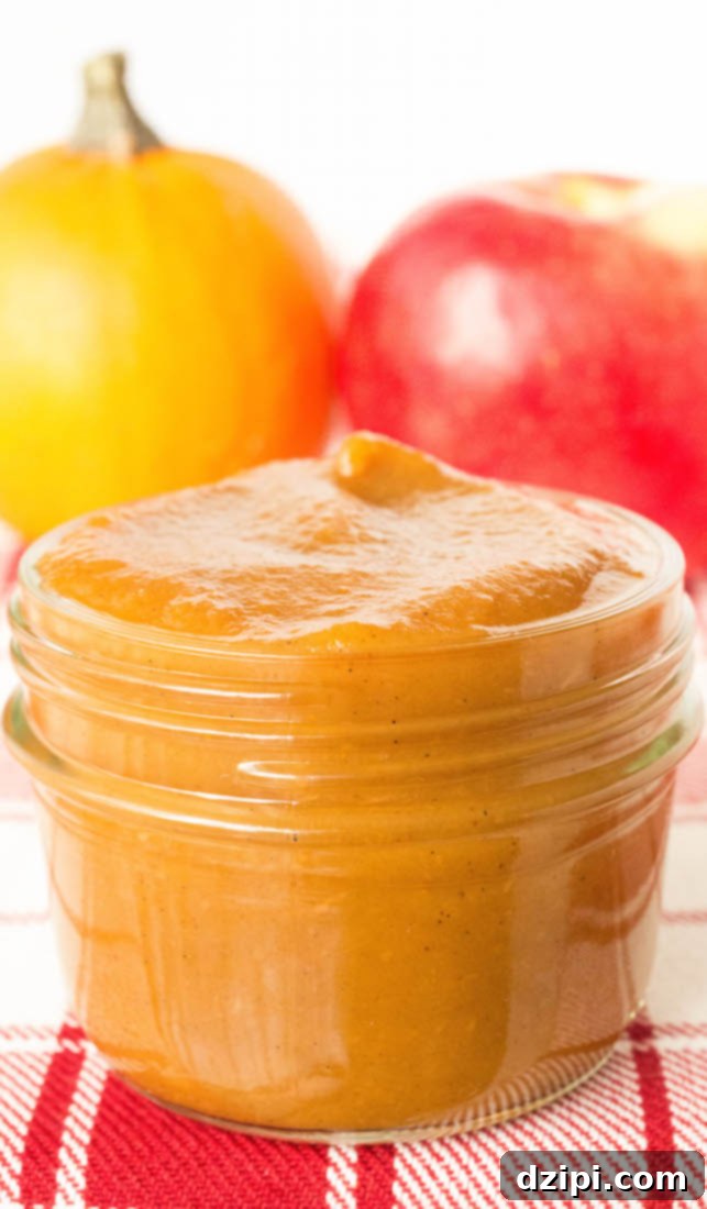 Close-up shot of a small, elegantly filled mason jar of homemade pumpkin apple butter, showcasing its smooth texture and rich color.