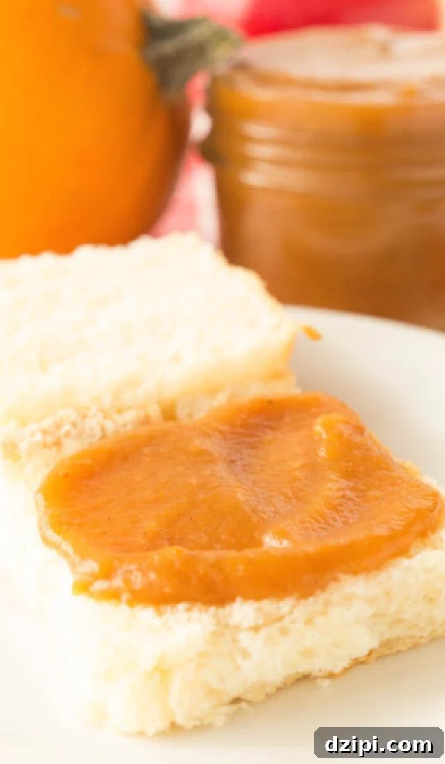 Homemade Vanilla Bean Pumpkin Apple Butter generously spread on a fluffy, golden Hawaiian roll, ready to be enjoyed as a sweet and comforting snack.