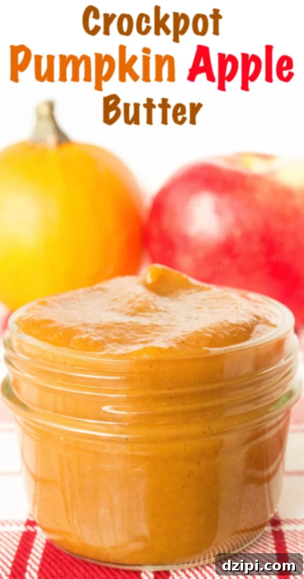 A charming still life featuring a small glass jar of homemade pumpkin apple butter. It rests in front of a decorative pumpkin and a fresh, whole apple, creating a quintessential autumnal display.