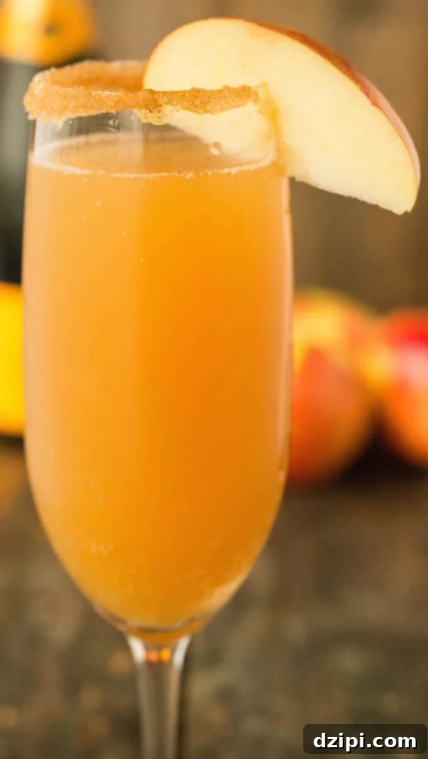 Apple cider mimosa in a champagne flute with a cinnamon sugar rim and apple slice.