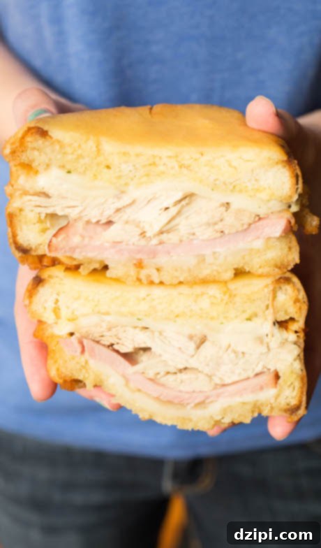 Post-Thanksgiving Texas Toast Monte Cristo 3 A Monte Cristo sandwich made with Thanksgiving leftovers has been sliced in half and is being held up by a pair of hands.