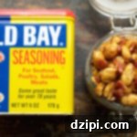 Overhead look at a glass jar filled to the top with Old Bay & bacon peanuts next to a can of old bay seasoning.
