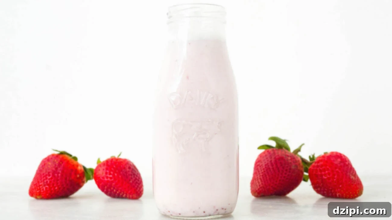 Homemade Strawberry Milk Recipe in a glass milk bottle on a white background.