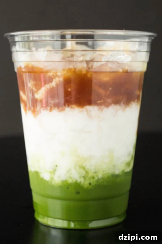 A Starbucks Matcha Espresso Fusion Drink with distinct layers of matcha, milk, and coffee on a black background.
