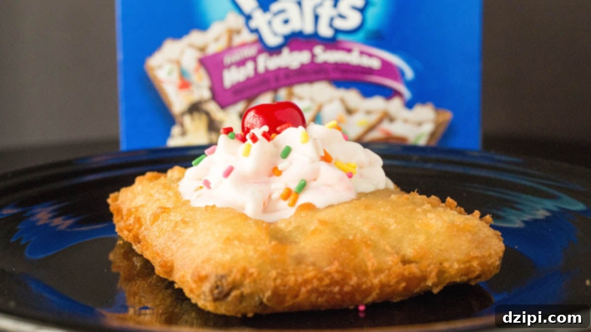Ultimate Deep Fried Pop-Tarts 2 A deep fried pop tart has been topped with whipped cream, sprinkles, and a cherry. It sits in front of an out of focus Pop-Tart box.