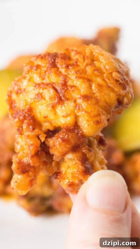 Fiery Nashville Hot Fried Oysters 3 Close up of a hand holding a single Nashville Hot Fried Oyster, showing its crispy exterior and spicy glaze.