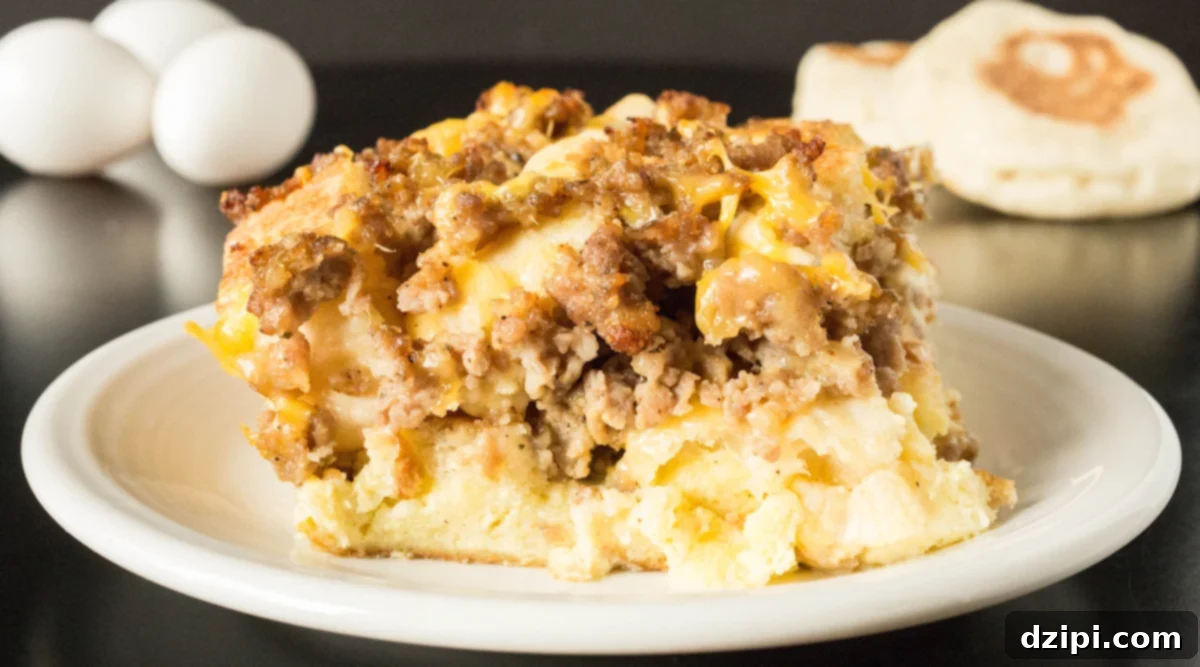 A slice of Sausage Egg McMuffin Casserole with eggs and English muffins out of focus in the background.