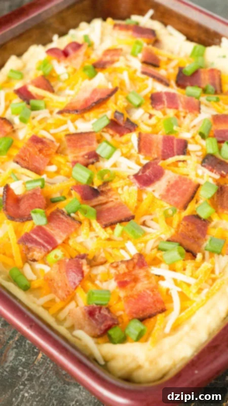 Instant Pot Loaded Potato Bake 4 A baking dish filled with Instant Pot Twice Baked Potato Casserole, lavishly topped with melted shredded cheese, crispy bacon pieces, and fresh green onions.
