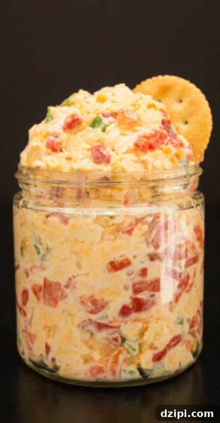 Homemade Pimento Cheese Recipe in a glass jar on a black background.