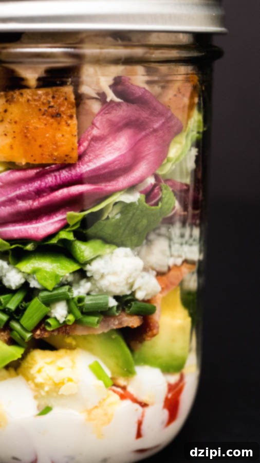 Ultimate Mason Jar Cobb Salad 3 Close-up view of the distinct layers of a Mason Jar Cobb Salad, showcasing fresh ingredients.
