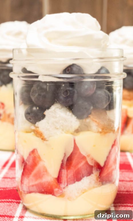 Close-up shot of a single Mason Jar July 4th Angel Food Cake Trifle, showcasing detailed layers of cake, berries, and cream for an individual serving.