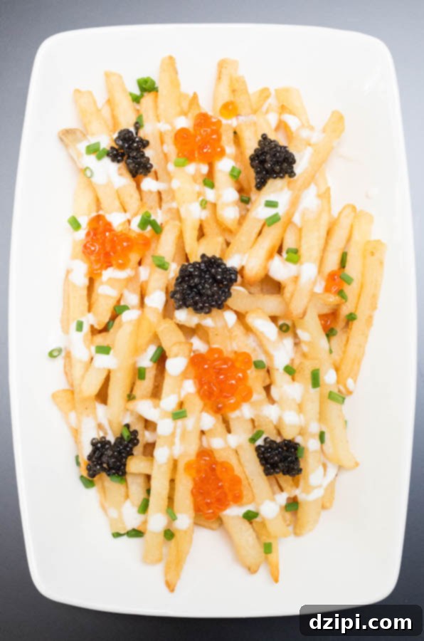 Overhead view of Caviar French Fries artfully arranged on a white serving plate, garnished with chives.