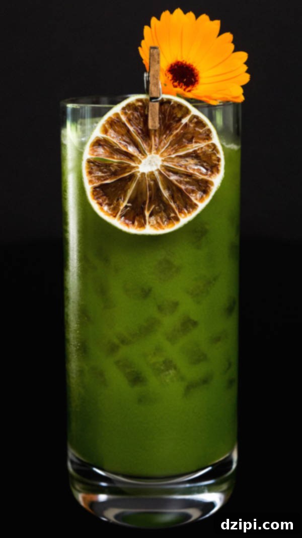 A Green Juice Margarita that's garnished with a dehydrated lime wheel and an orange edible flower, highlighting its exquisite presentation.