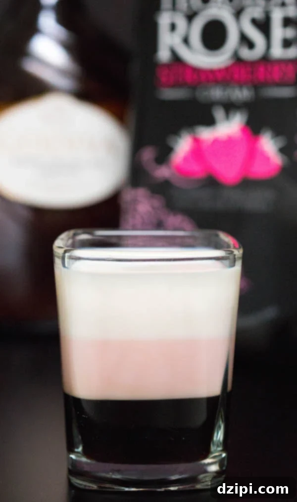 A layered Neapolitan shot with Tequila Rose and Godiva White Chocolate Liqueur in the background.